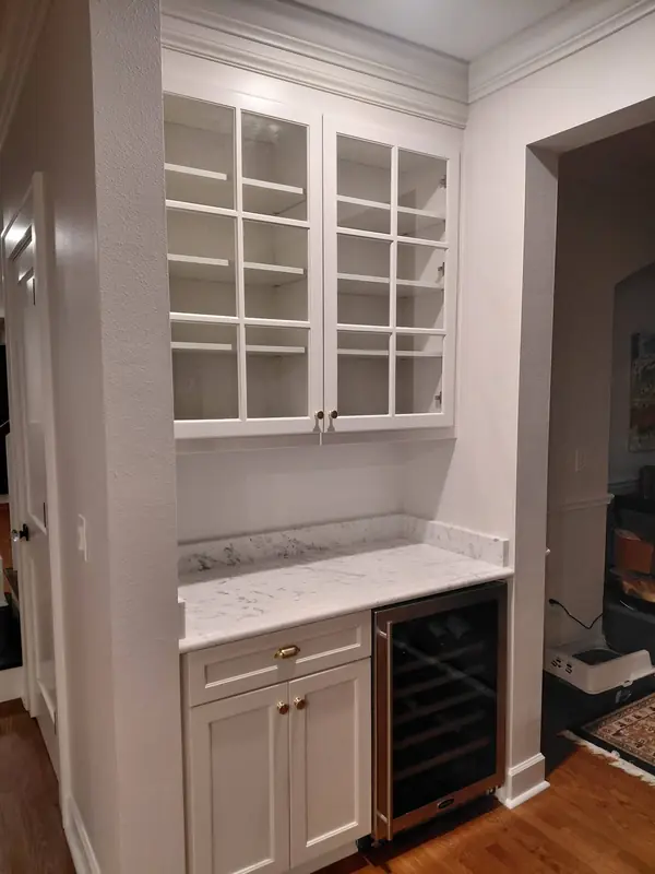 White built-in cabinet with glass doors above a wine fridge