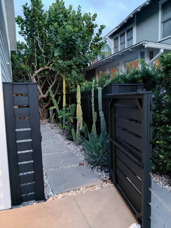 Black horizontal-slat fence and gate beside a stone path