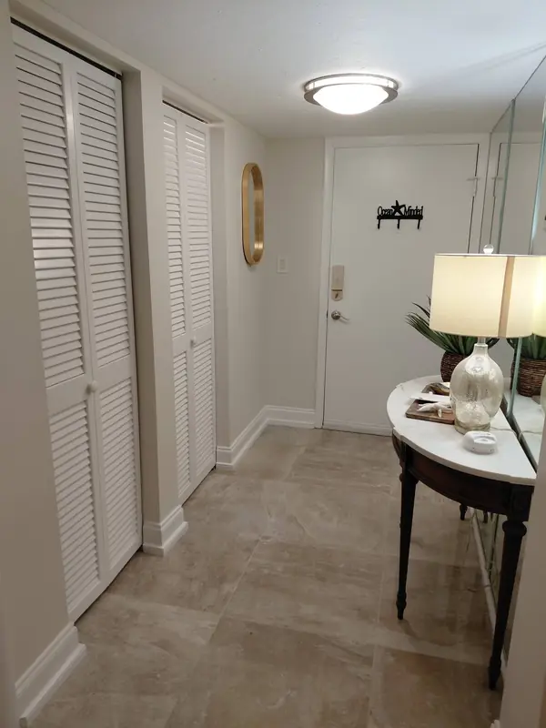 Bright entry with white louvered closet doors and a marble-top console table