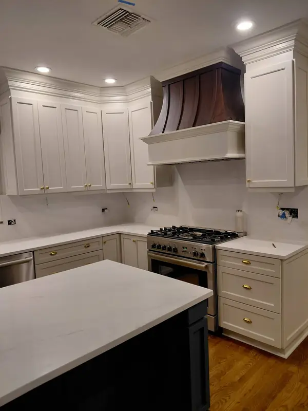 White shaker kitchen cabinets with a range hood and brass hardware