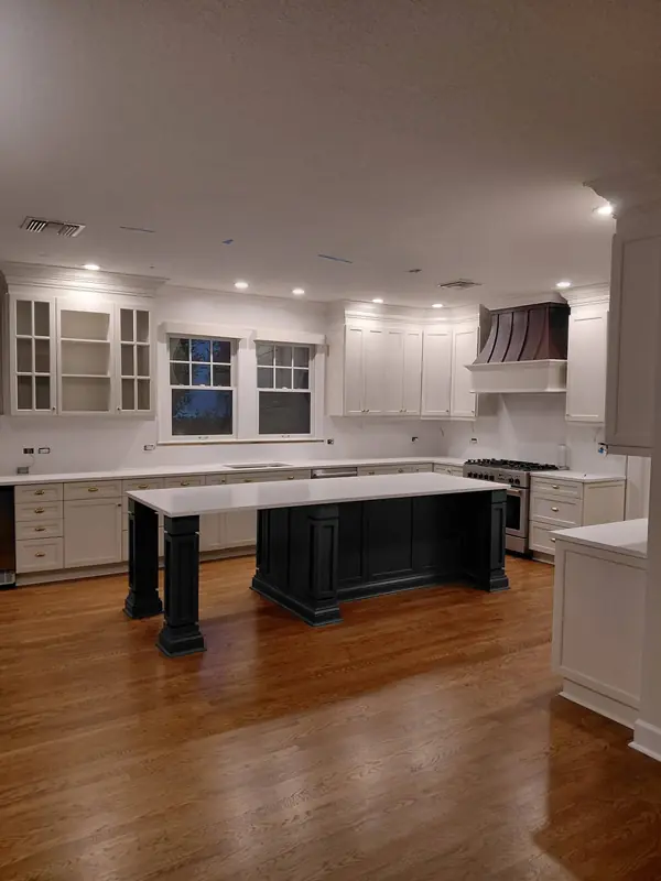 White kitchen cabinets with glass-front uppers around a black painted island