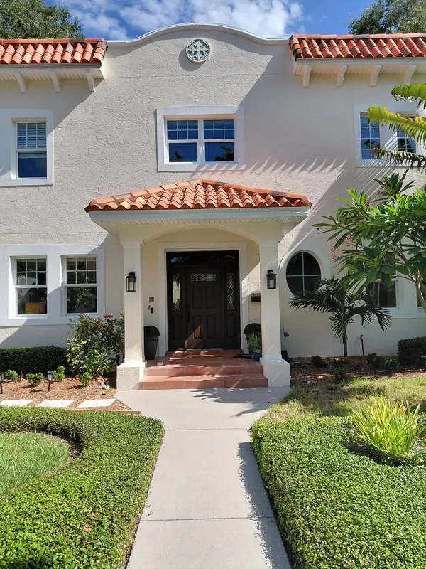 Cream stucco Mediterranean-style house with a red tile roof and white window trim