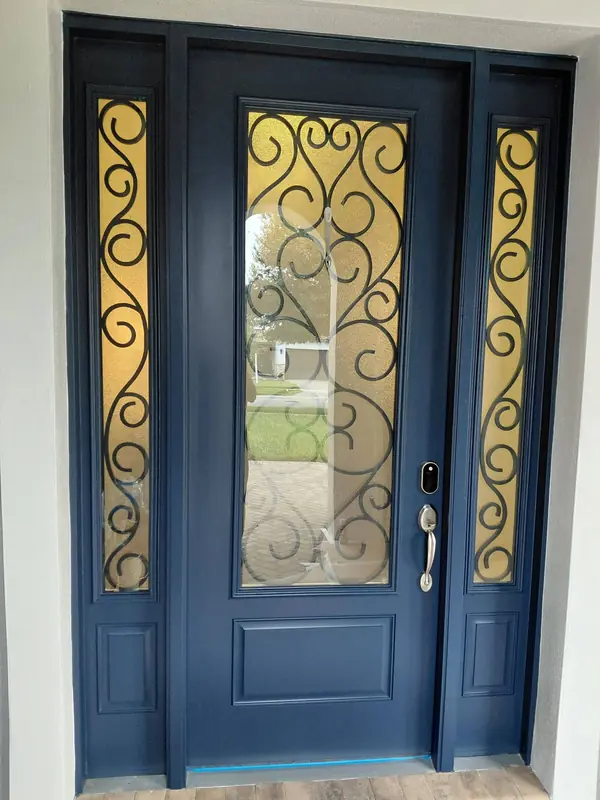 Navy blue front door with decorative iron-and-glass panels and matching sidelights