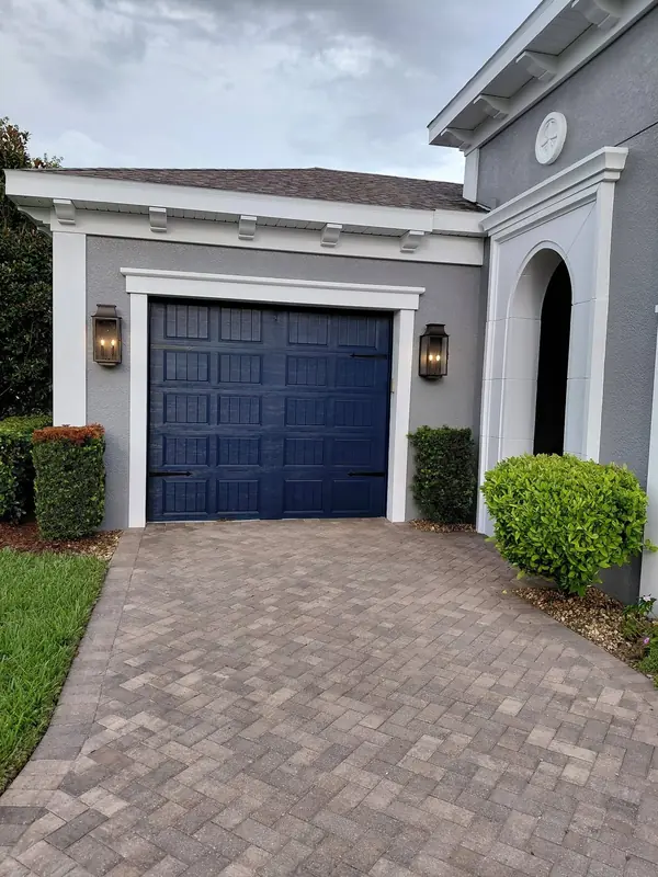 Navy blue garage door framed in white trim on a gray stucco house