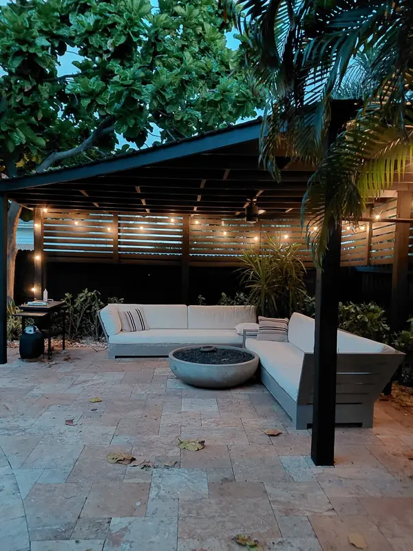 Covered patio under a black-painted pergola with string lights